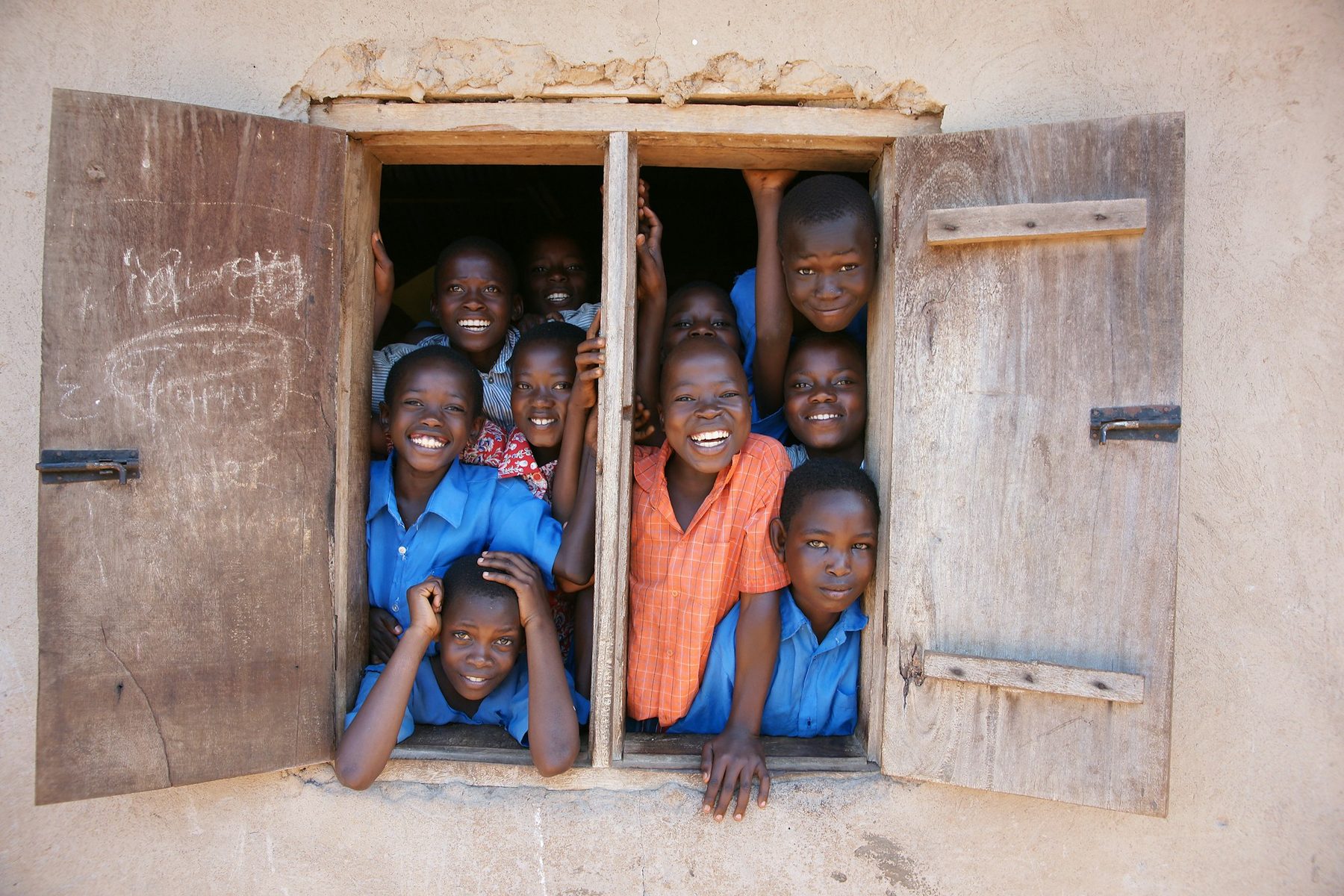Children smiling through an open classroom window