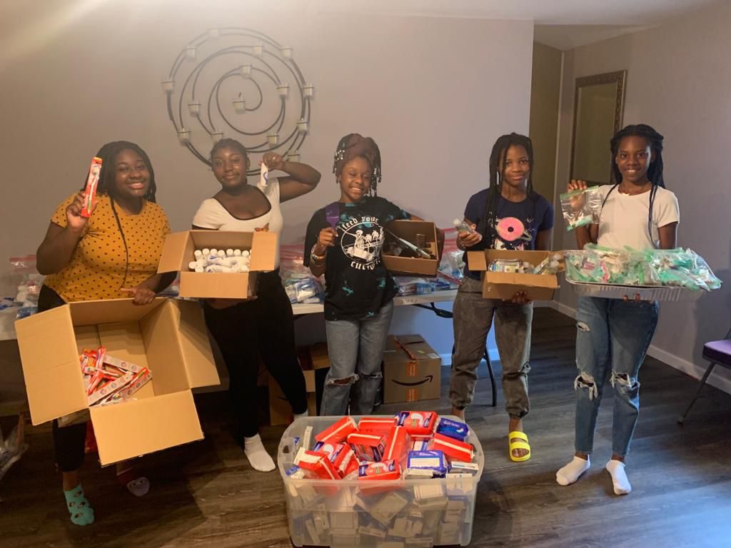 Salone Millennials volunteers smiling beside boxes of hygiene supplies